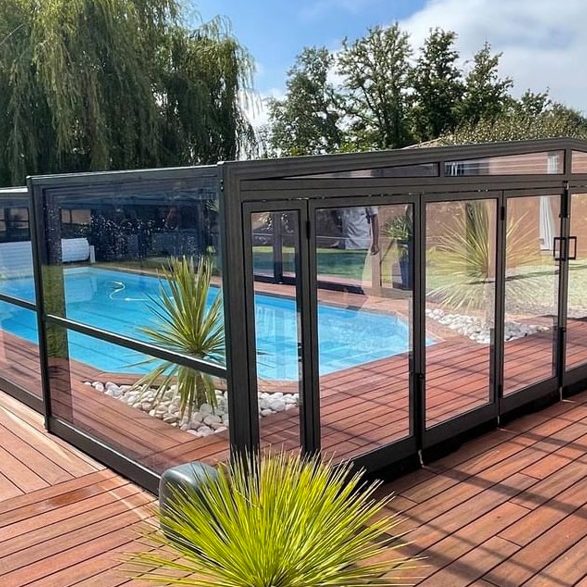 Abri autour d'une piscine avec des plantes et un patio en bois.